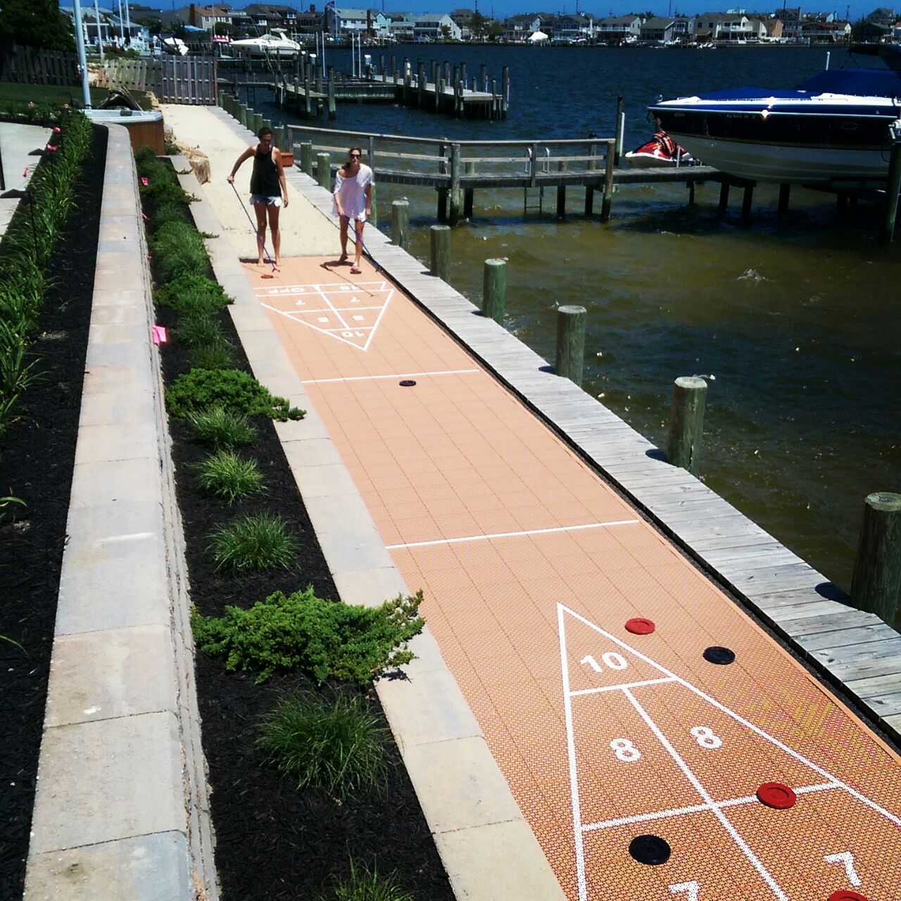 People playing shuffleboard on a dock with a boat in the background