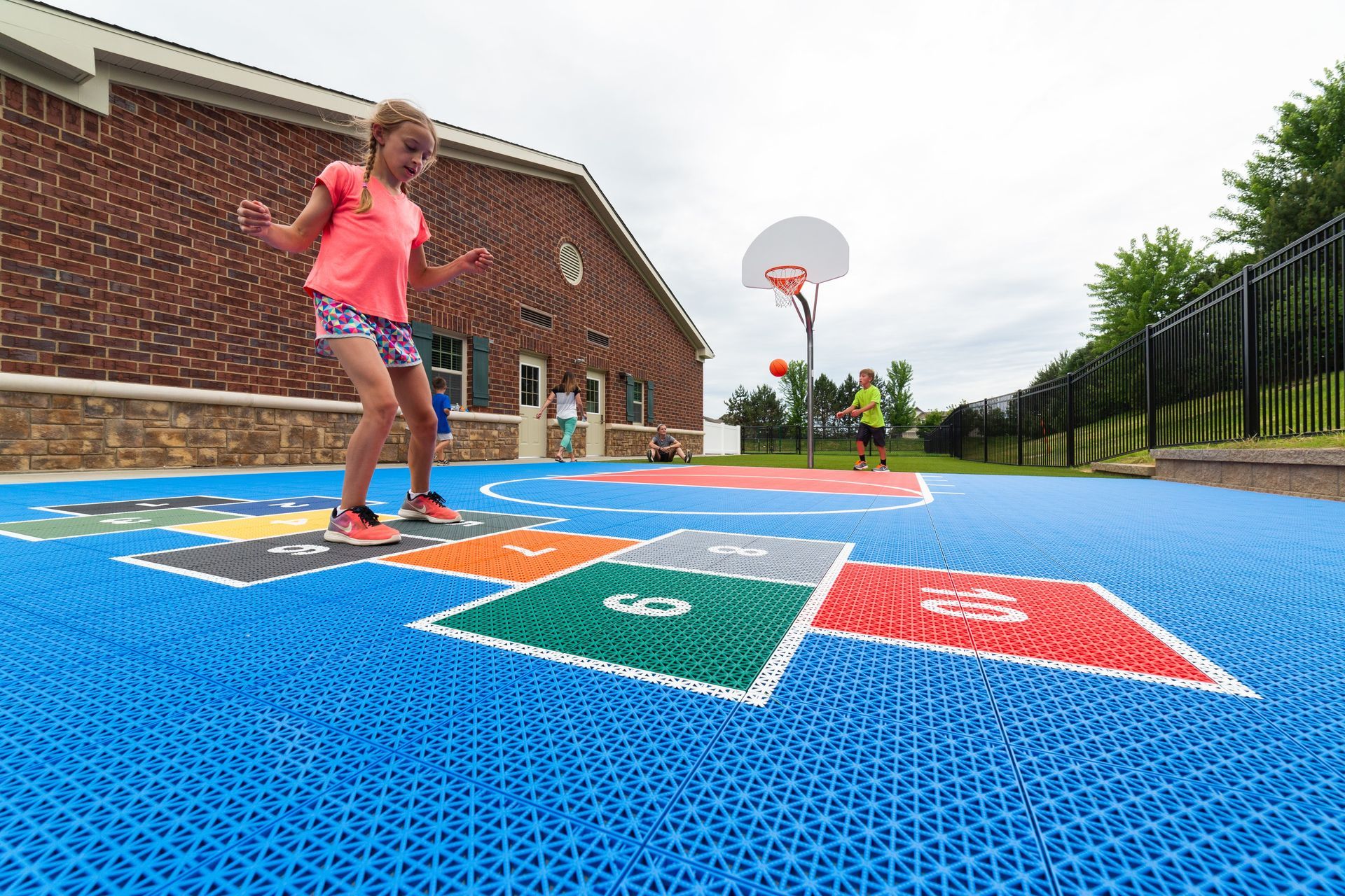 A little girl is playing hopscotch in a playground.