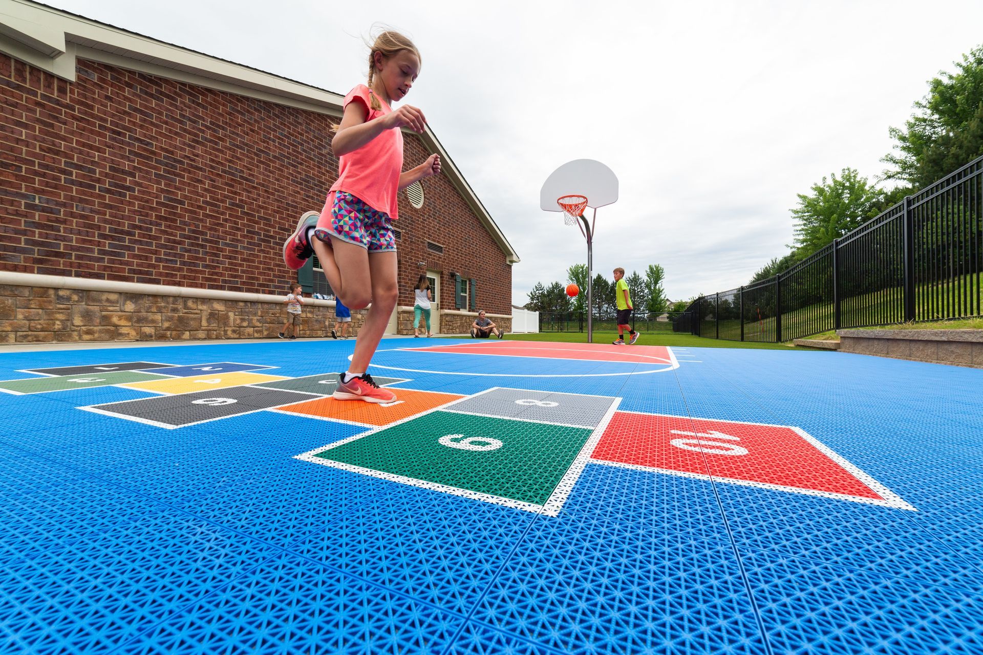A young girl is jumping in a hopscotch game on a playground.