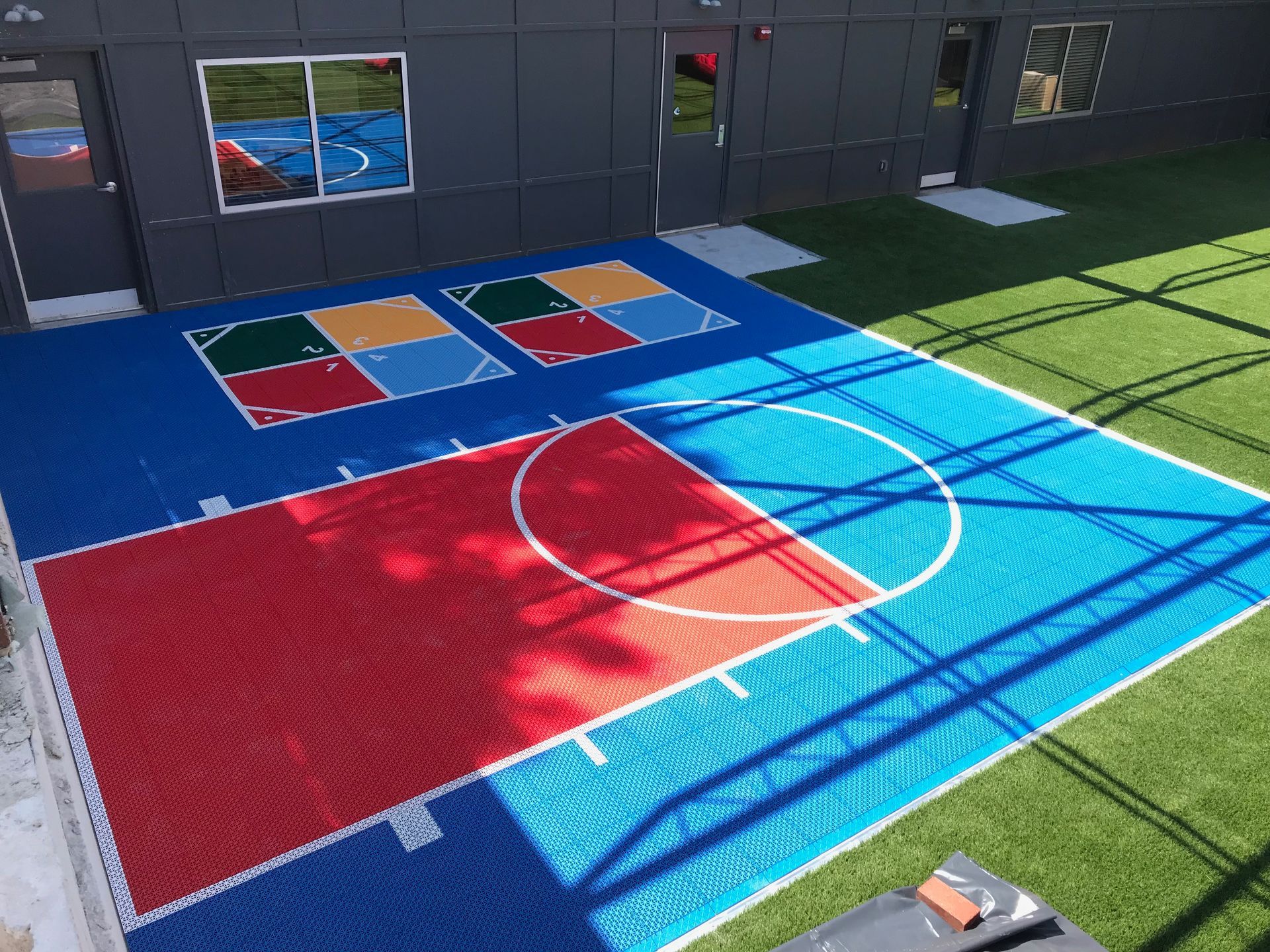 An aerial view of a colorful basketball court in front of a building.