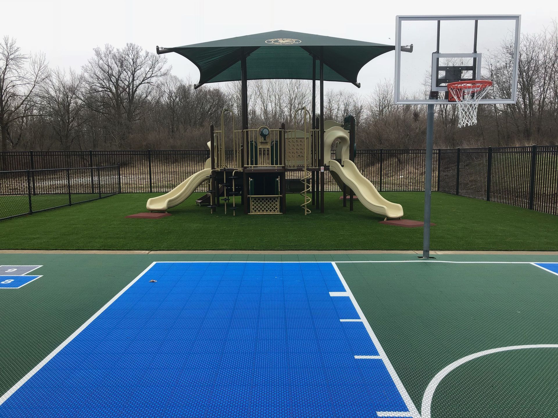 A basketball court with a playground in the background