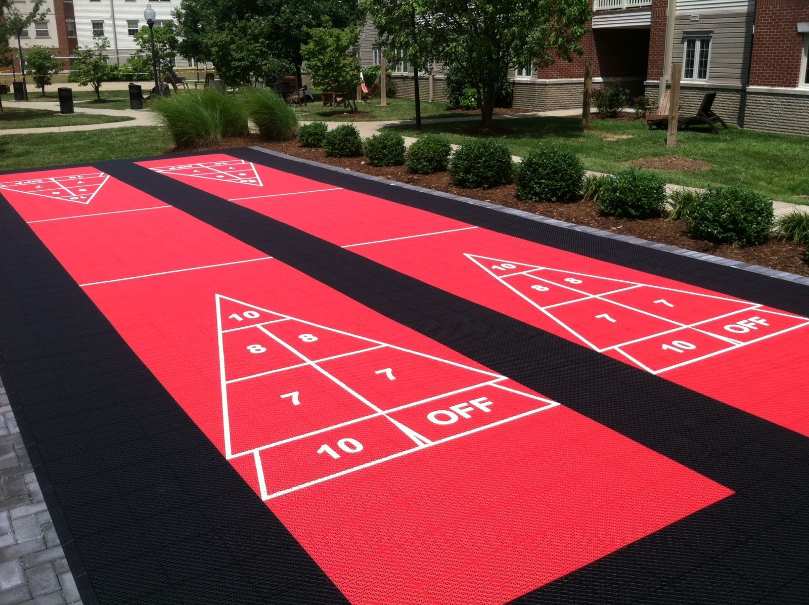 A red and black shuffleboard court in a park