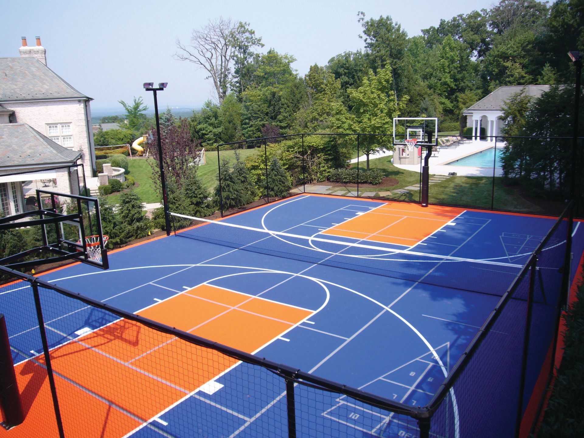 A blue and orange basketball court with a pool in the background