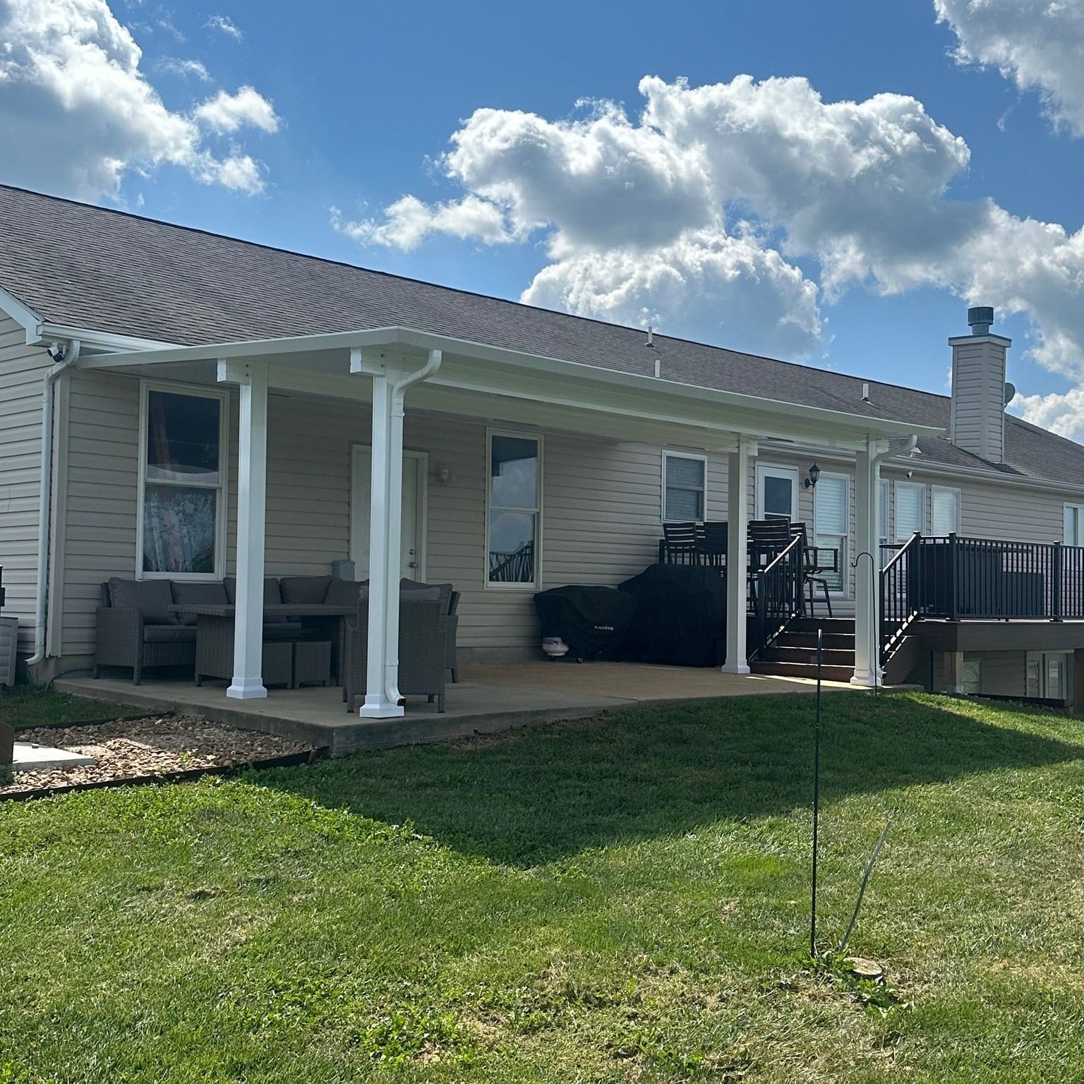 A white house with a porch and a deck in the backyard.