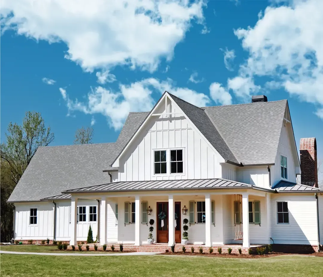 A large white house with a gray roof and a large porch.