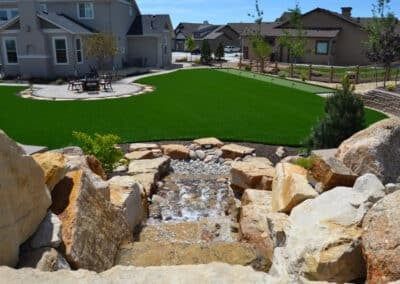 There is a waterfall in the middle of a lush green lawn.