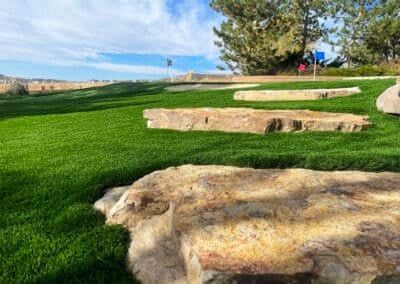 A lush green field of grass with rocks in the foreground.