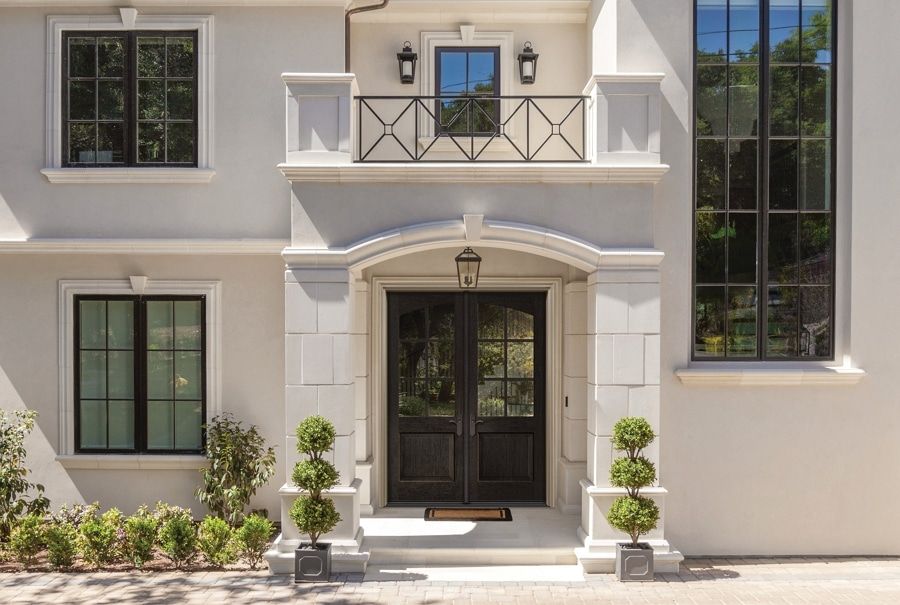 The front of a white house with black windows and a black door.
