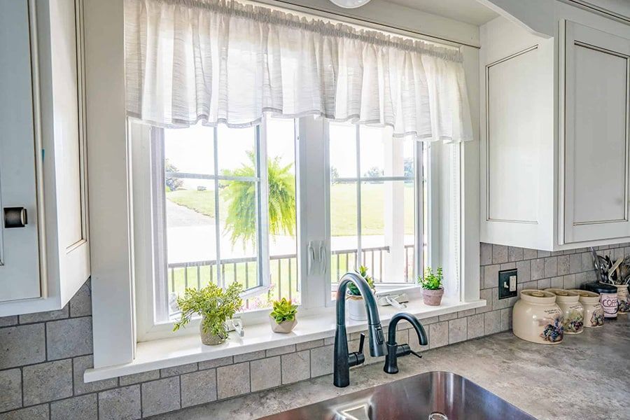 A kitchen with a sink and a window with plants on it.