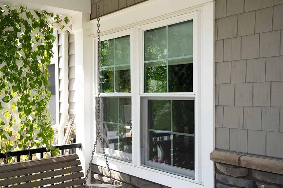 A porch with a swing and a window on the side of a house.