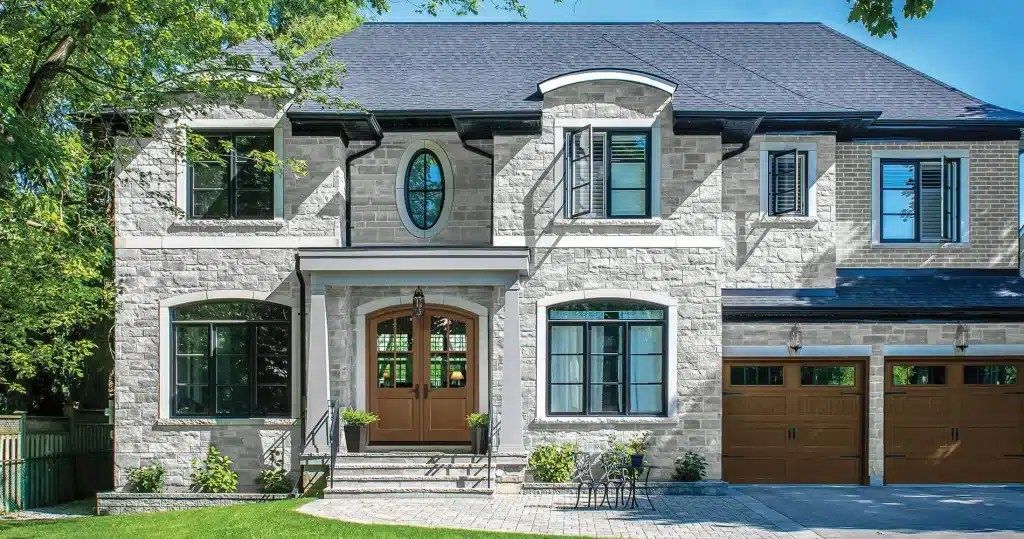 A large brick house with a blue roof and two garages.