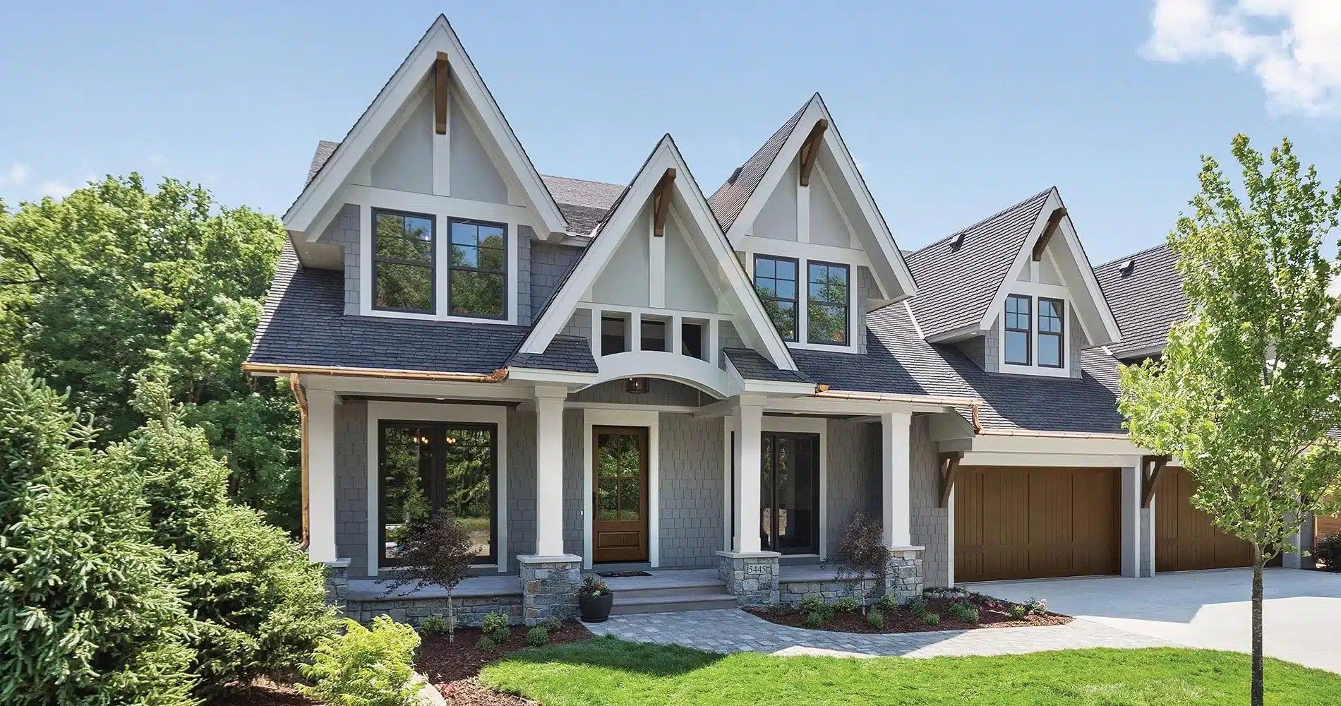 A large house with a lot of windows is sitting on top of a lush green lawn.