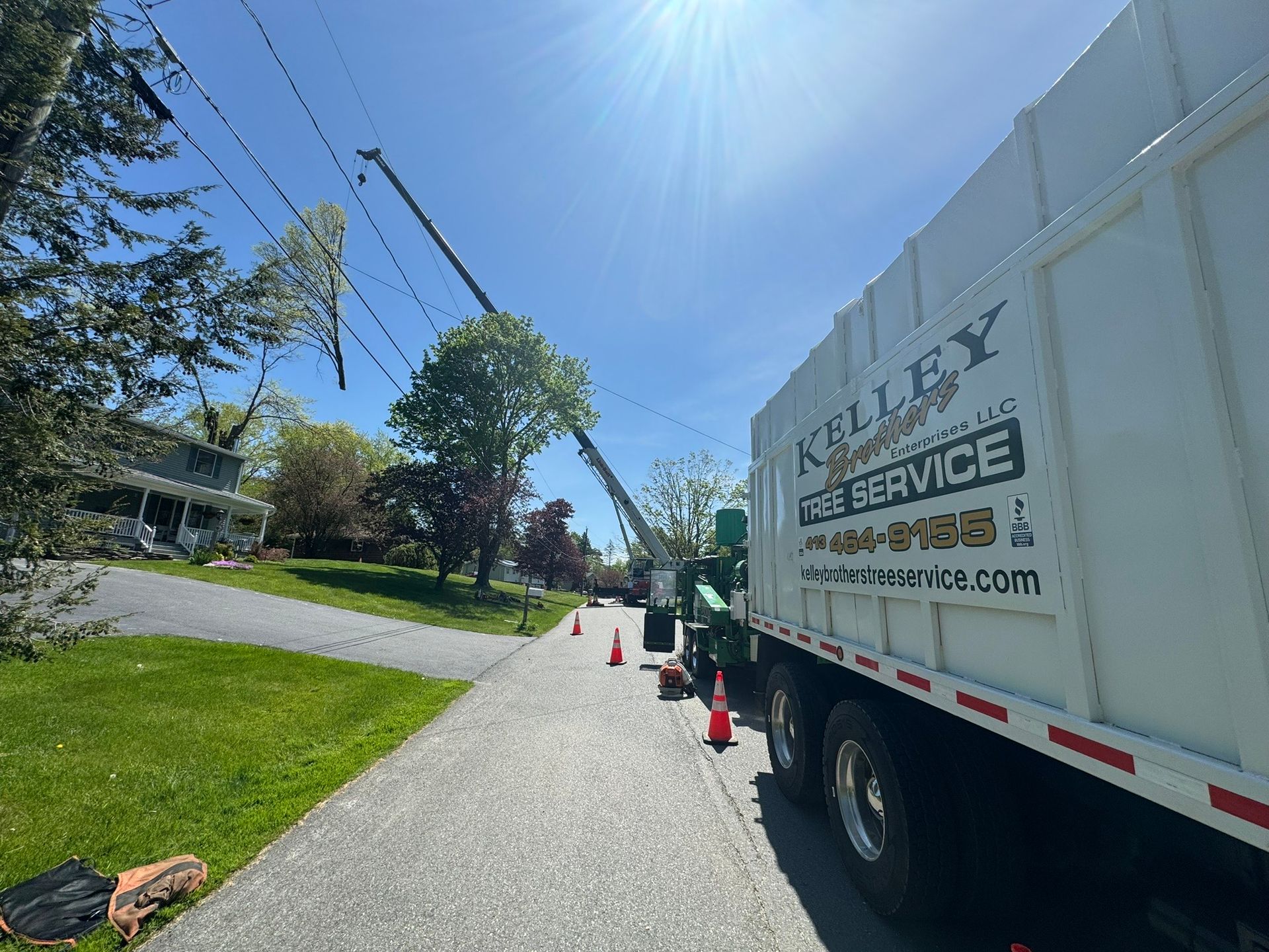 A white truck with a crane attached to it is parked on the side of the road