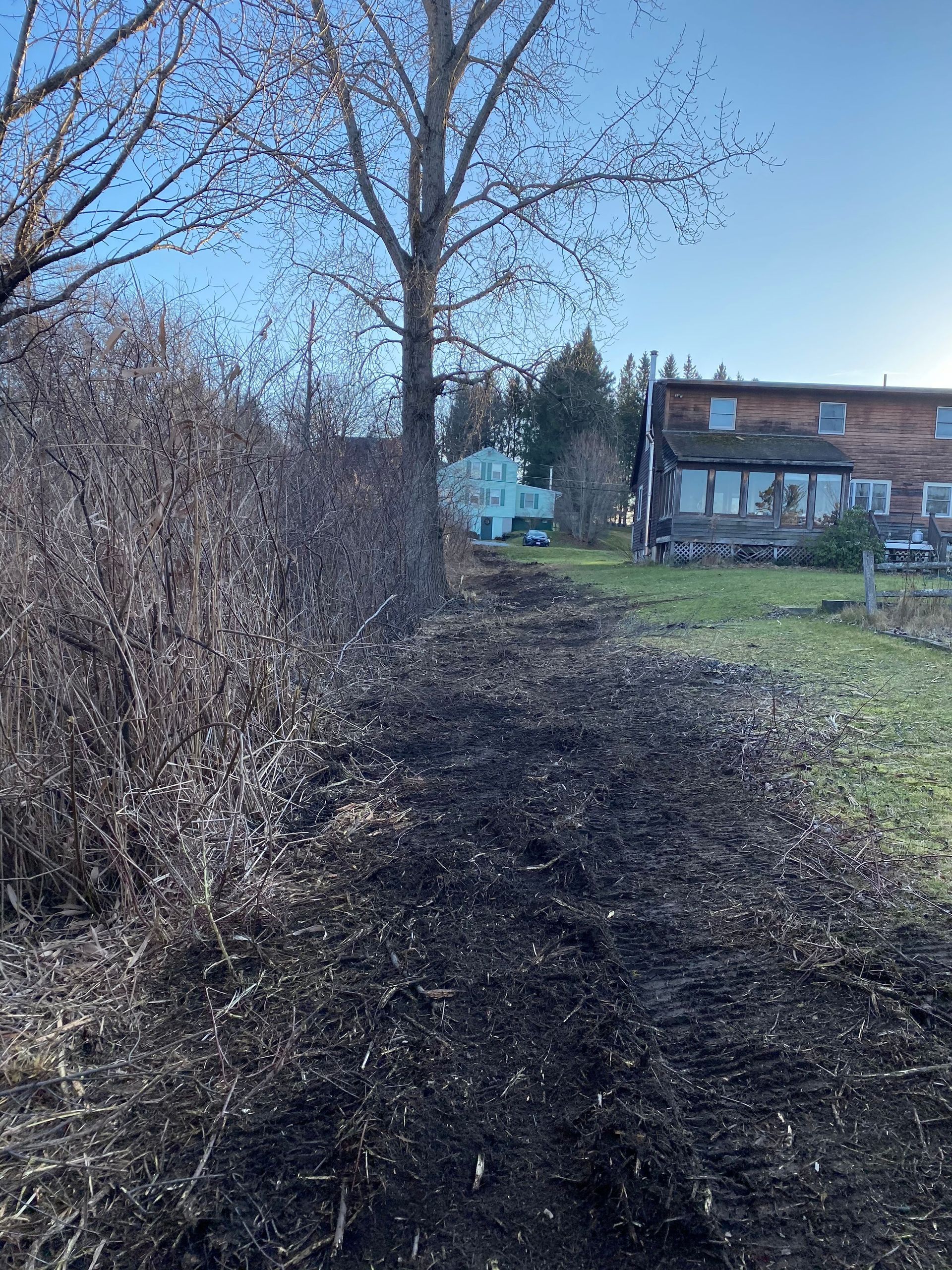 There is a house in the background and a pile of dirt in the foreground.