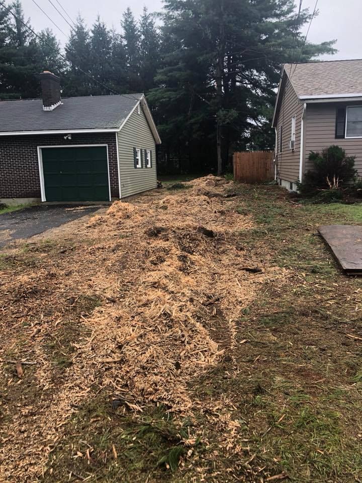 A house with a garage and a lot of wood chips in front of it.