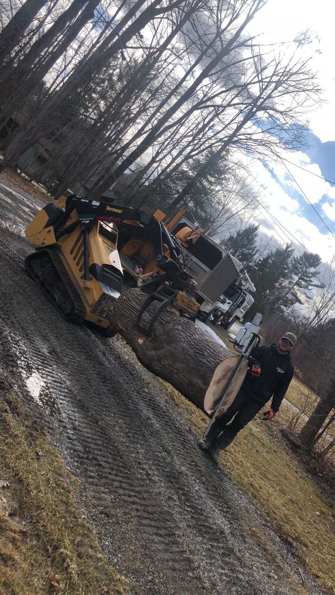 A man is walking down a dirt road next to a tractor.