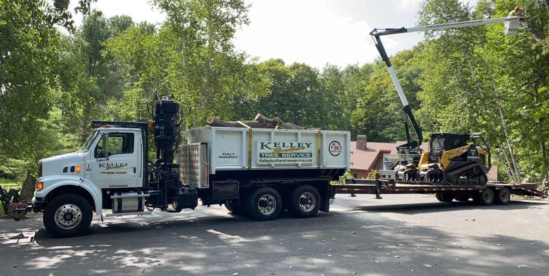 A dump truck with a crane attached to it is parked next to a bulldozer.