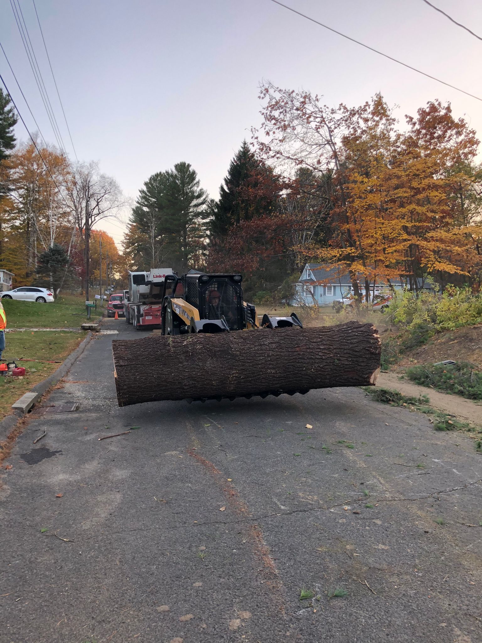 A bulldozer is carrying a large log down a street.