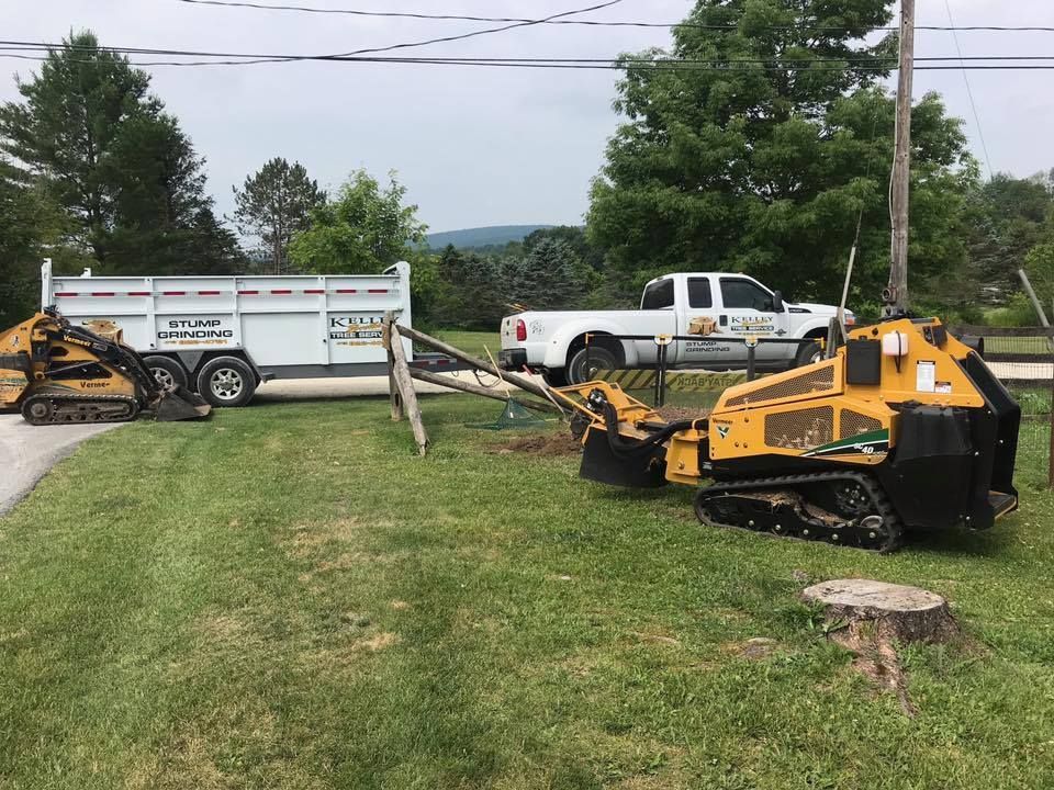 A truck is towing a stump grinder in a yard.