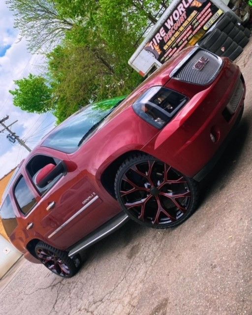 A red car is parked in front of a tire world truck