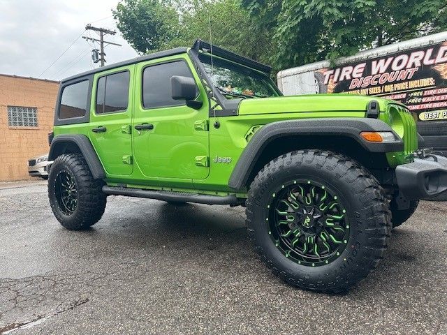 A green jeep is parked in front of a tire shop.