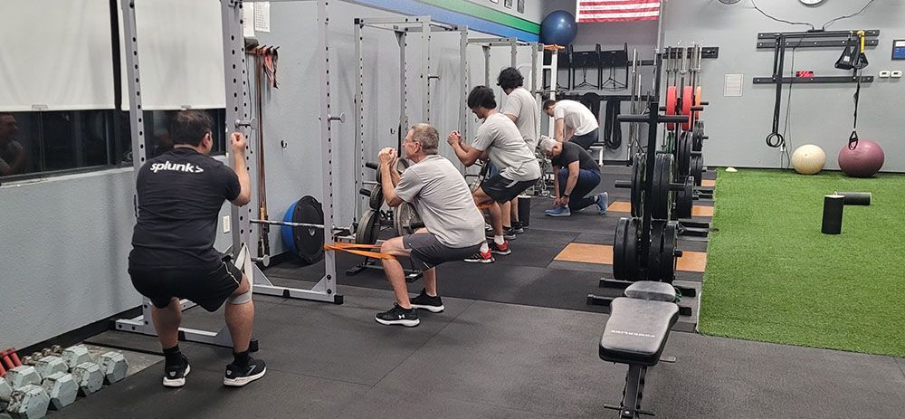A group of people are doing squats in a gym.