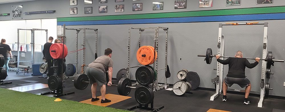 A group of people are lifting weights in a gym.
