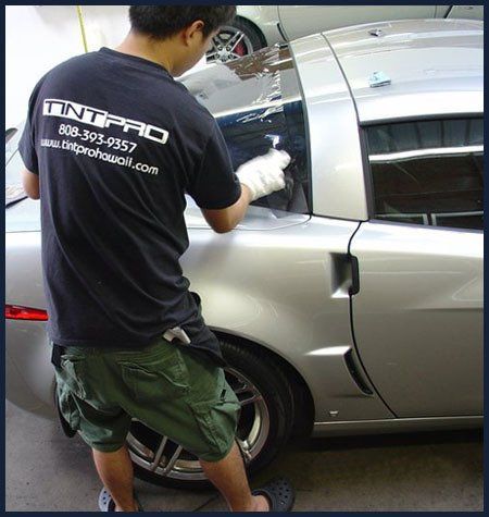 Workman adding a tint to the car glass