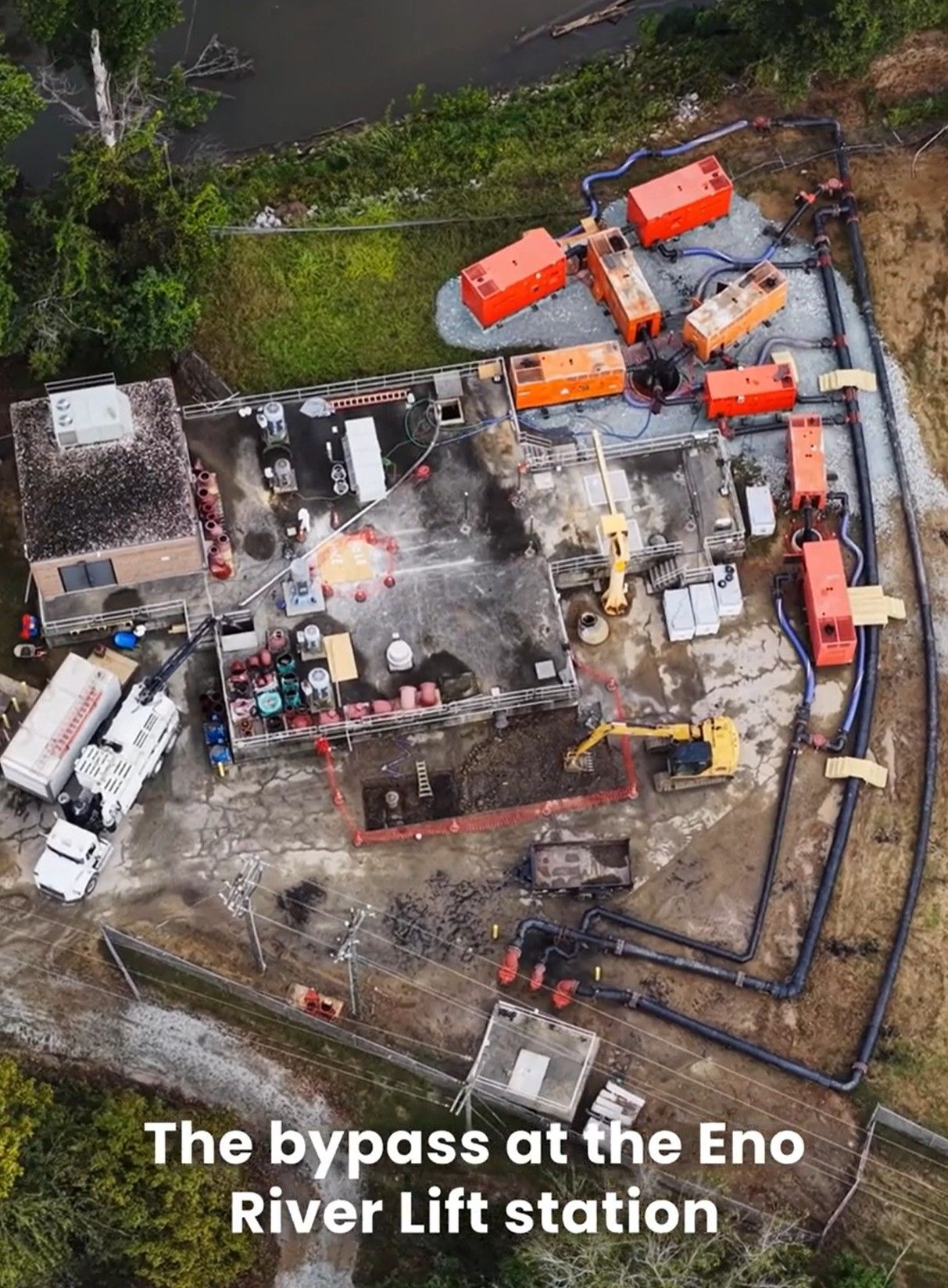 Aerial view of orange pumping equipment and black hoses set up at the Eno River lift station for a sewage bypass operation.