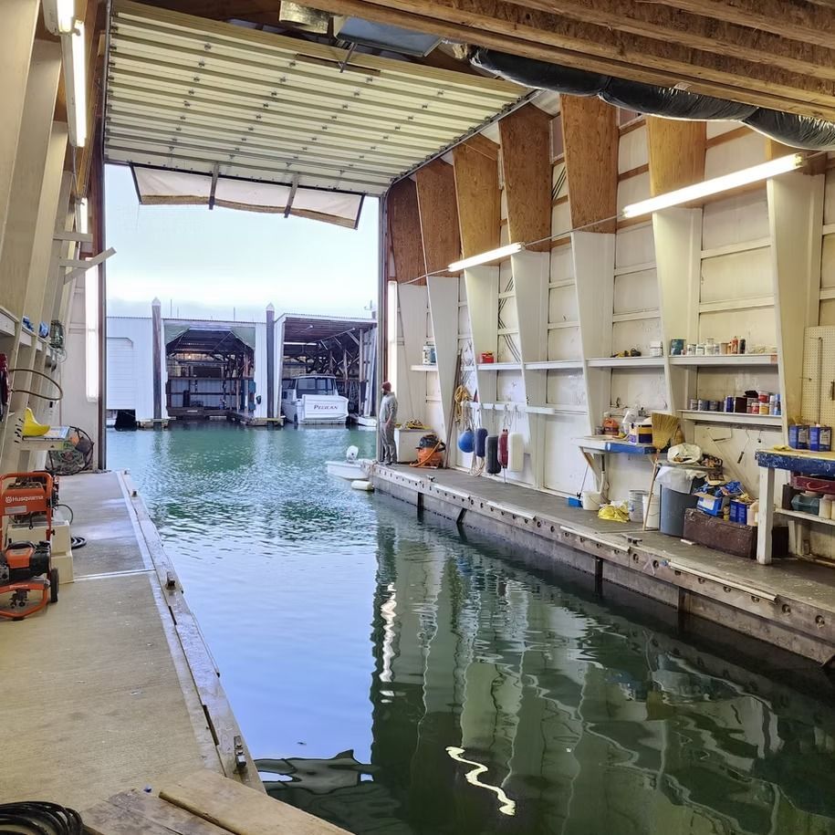 A boat is docked in a garage with the door open