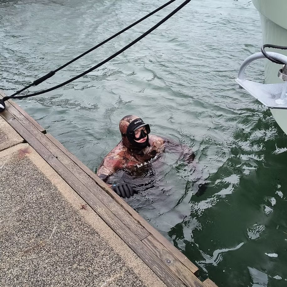 A man in a wet suit is swimming in the water