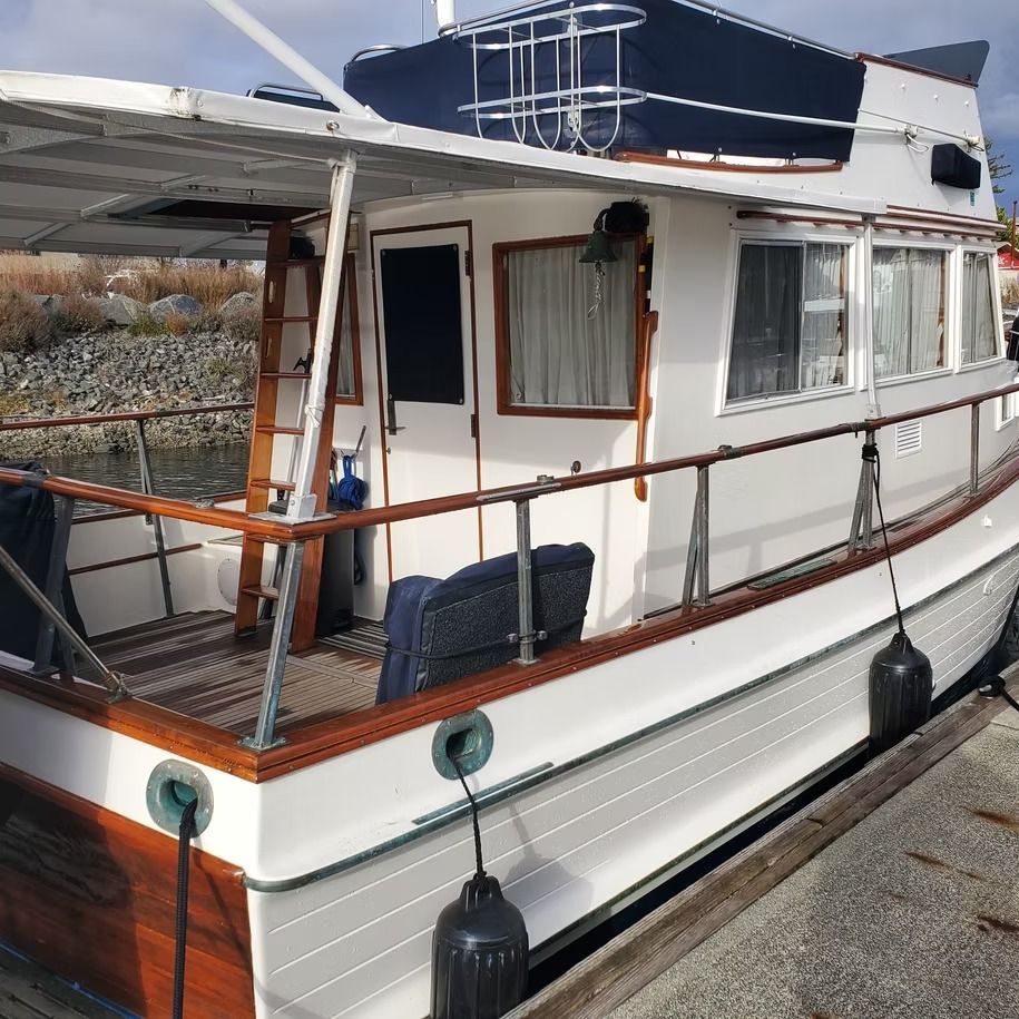 A white boat with a wooden deck is docked at a dock