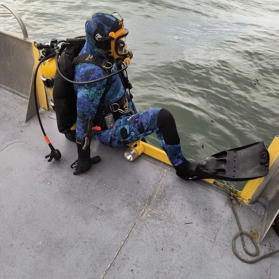 A scuba diver is sitting on the deck of a boat