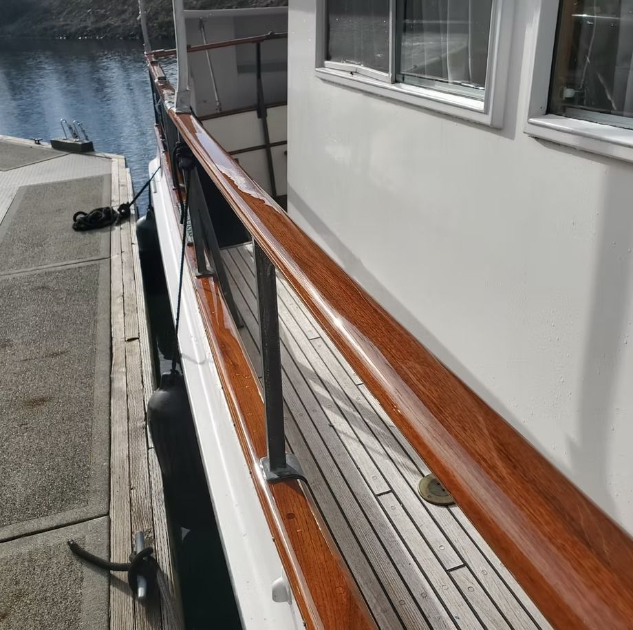 A boat with a wooden railing is docked at a dock