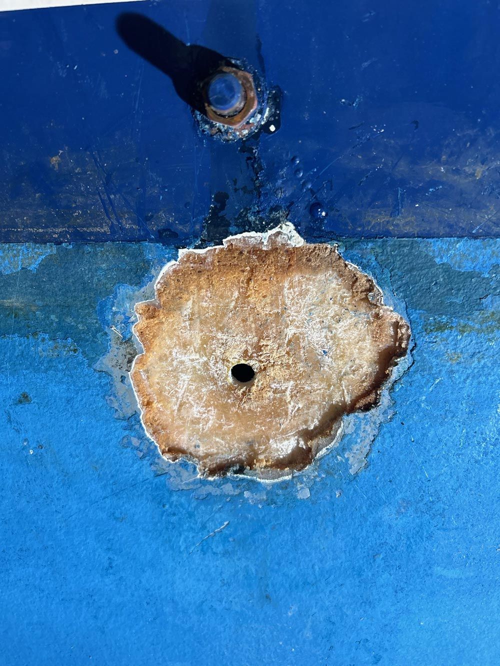 A hole in the side of a blue boat with a hole in it.