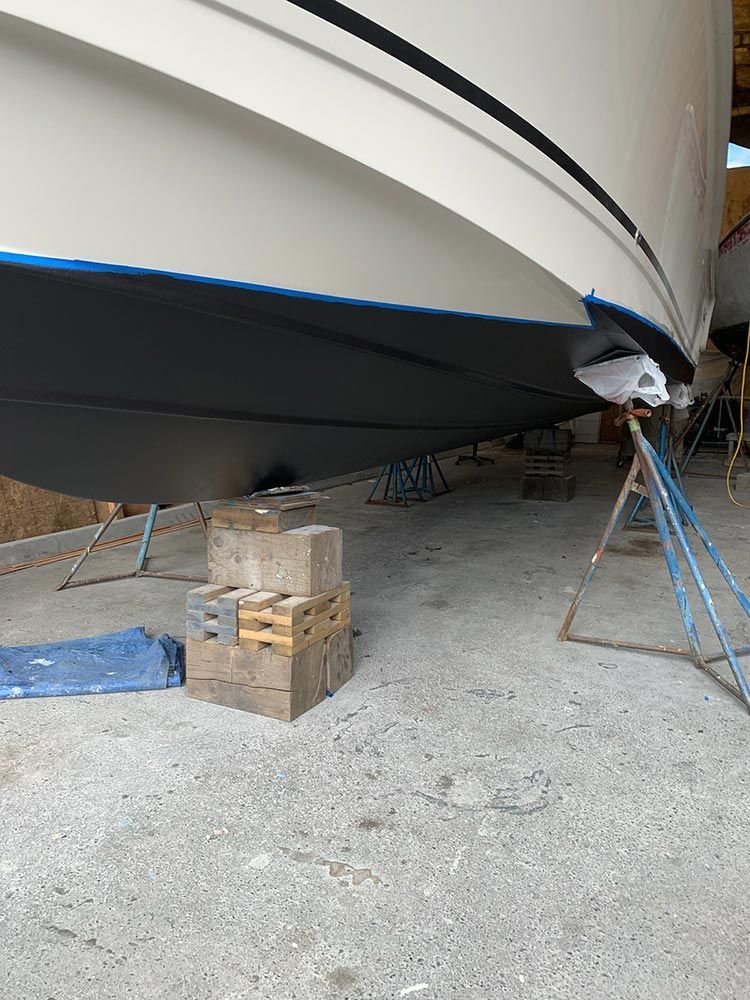 A boat is sitting on a cement floor in a warehouse.