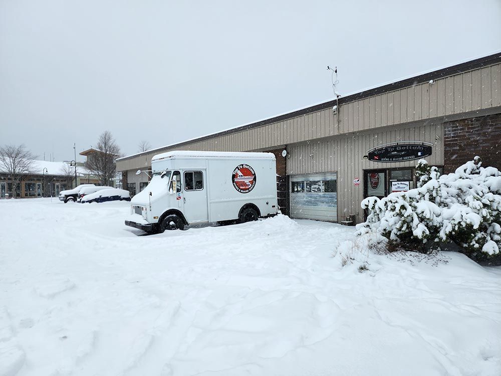 A white van is parked in the snow in front of a building.