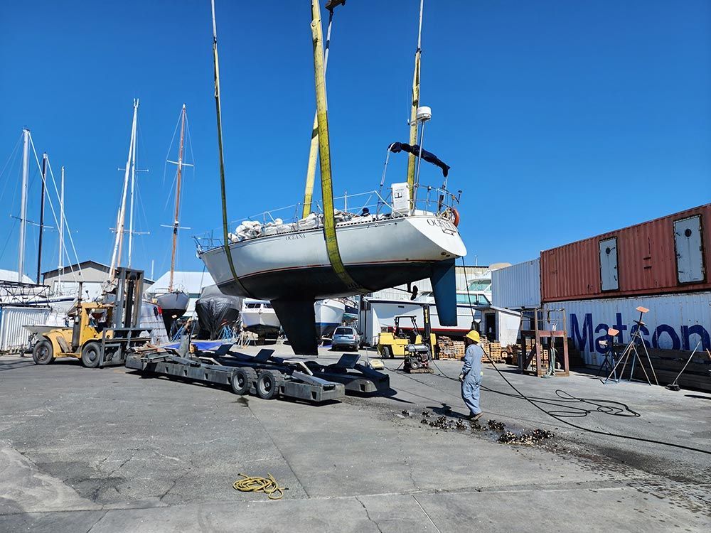 A boat is being lifted by a crane in a marina