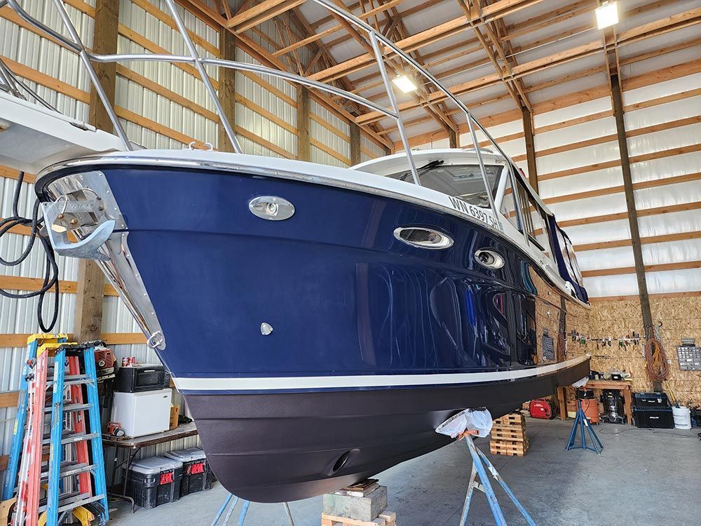A blue boat is sitting in a wooden shed.