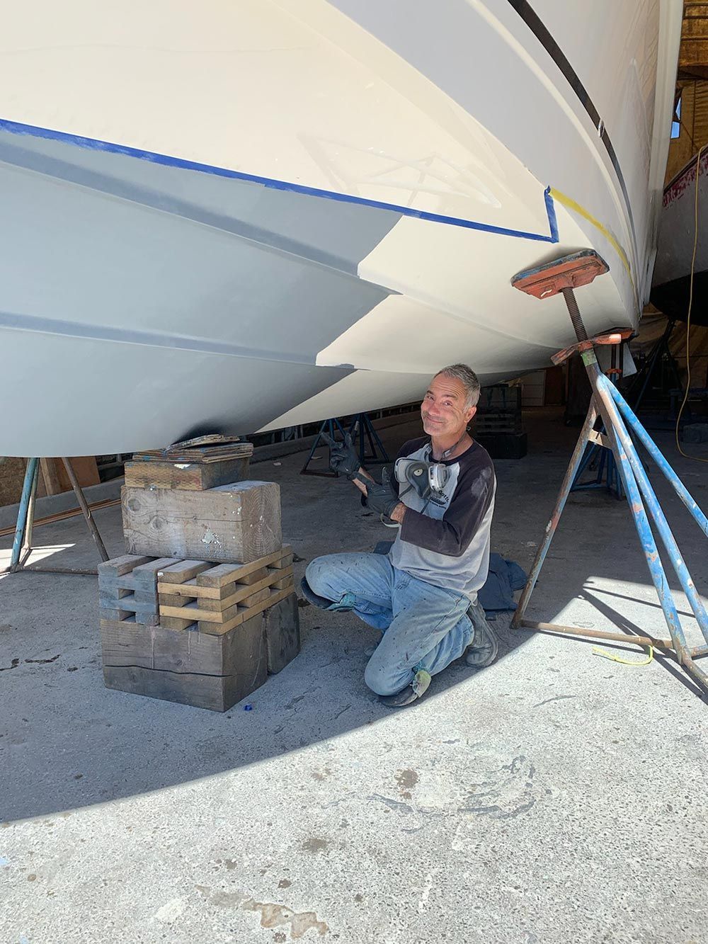 A man is kneeling down in front of a boat.