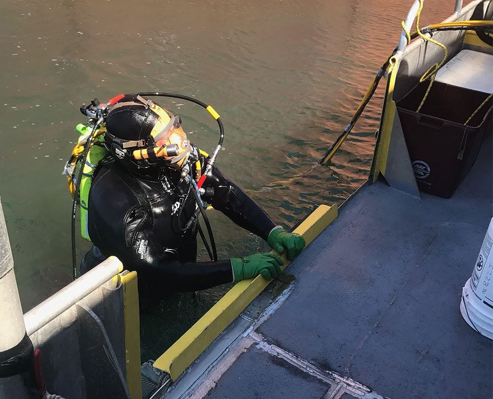 A scuba diver is sitting on the side of a boat in the water.