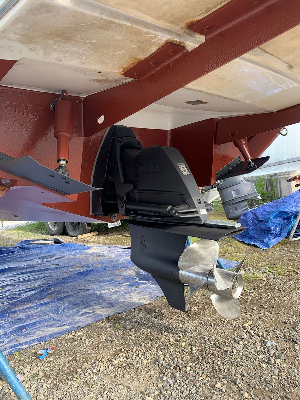 A boat engine is sitting on top of a pile of gravel.