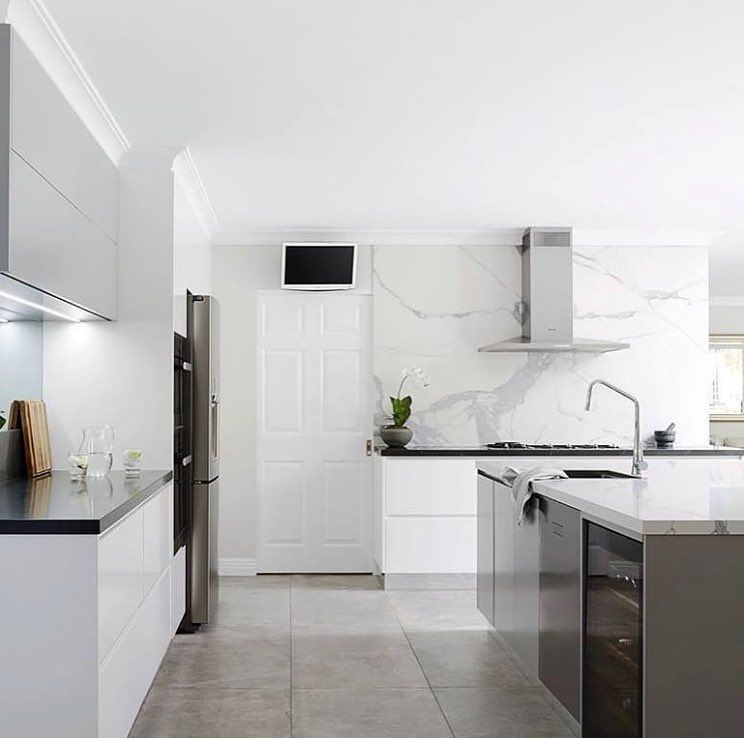 Modern kitchen with white cabinetry, stainless steel appliances, and marble backsplash.