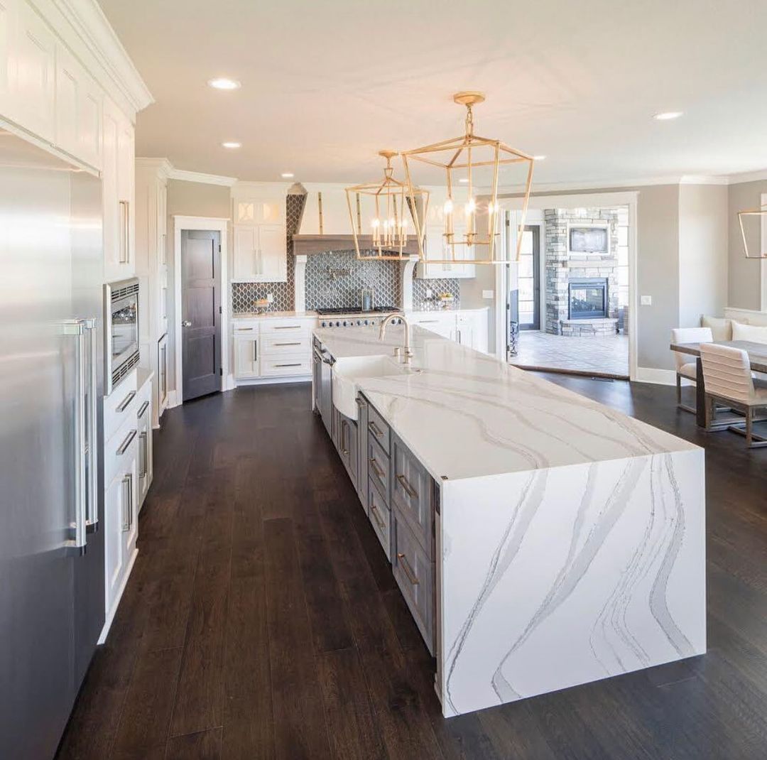 Spacious modern kitchen with a large island, stainless steel appliances, and dark wood floors.