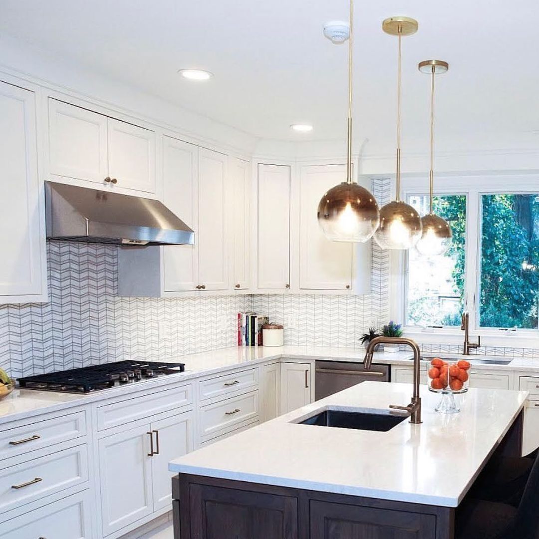 Modern kitchen with white cabinets, island, and pendant lights.