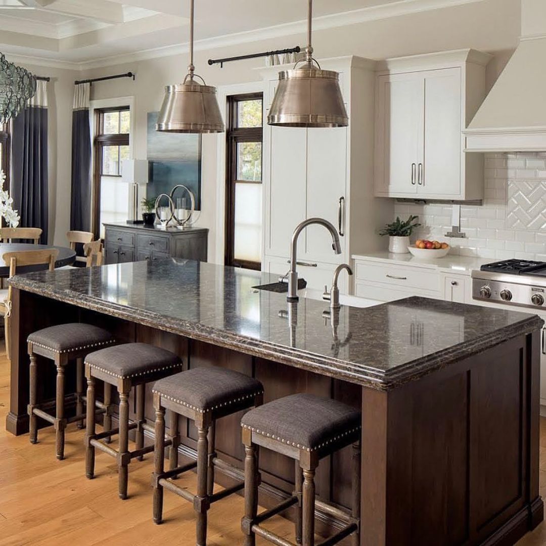 Kitchen island with granite countertop, dark cabinetry, and four upholstered stools.