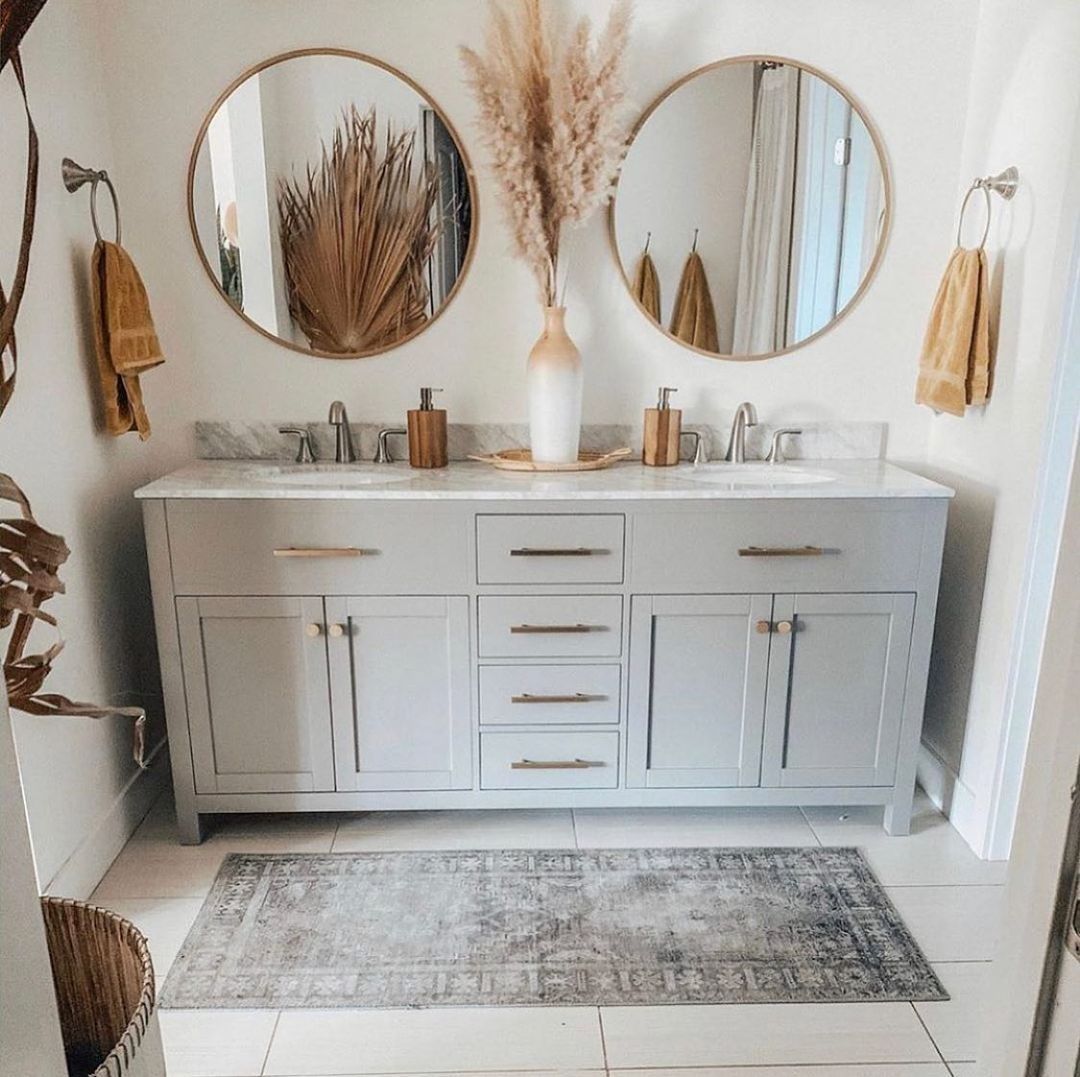 A modern bathroom with a double vanity, round mirrors, and neutral decor.