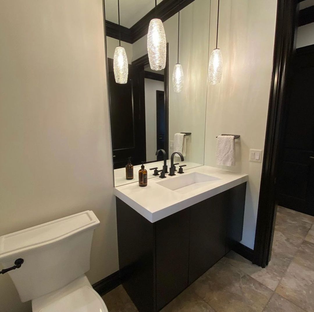 Powder room with dark cabinetry, white sink, and pendant lights over a mirror.