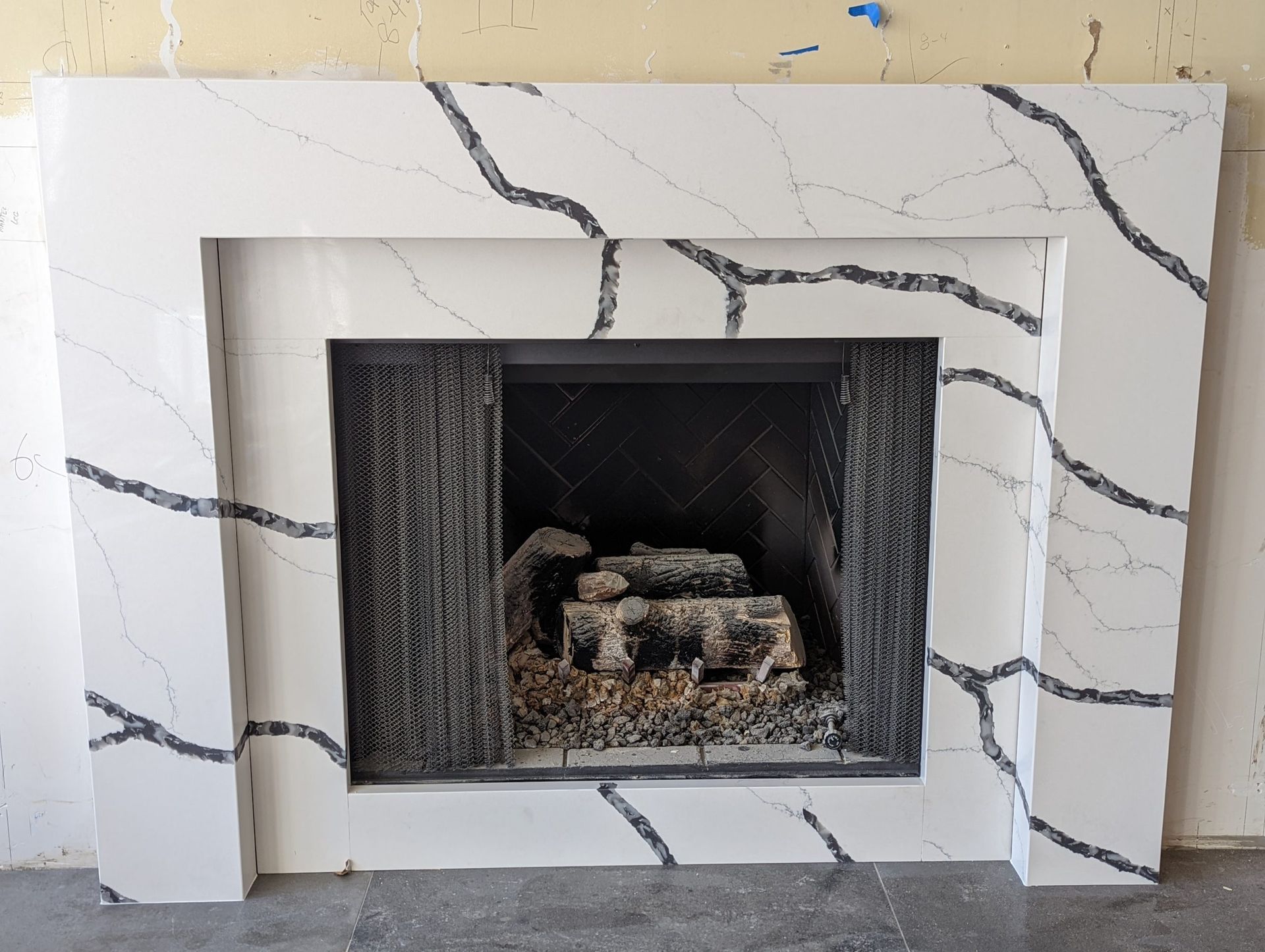 White fireplace with black veining, an inset black firebox, and a gray hearth.