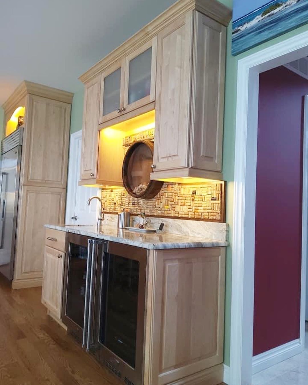 Built-in wet bar with wood cabinets, wine coolers, and a small sink against a mosaic tile backsplash.